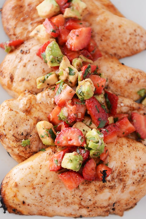 Four large grilled chicken breasts topped with a strawberry-avocado salsa.