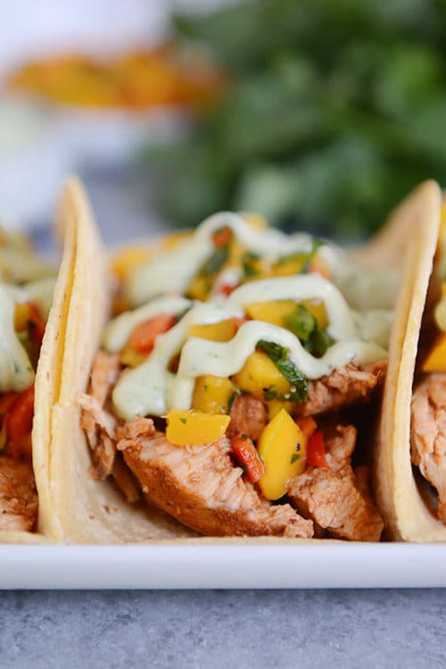 A pork taco in a corn tortilla topped with mango salsa and dressing.