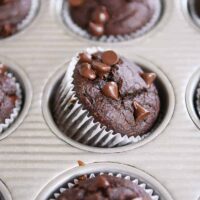 Double chocolate banana blender muffin propped on side in metal tin.