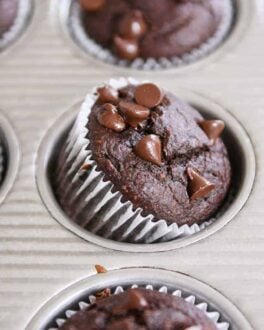 Double chocolate banana blender muffin propped on side in metal tin.