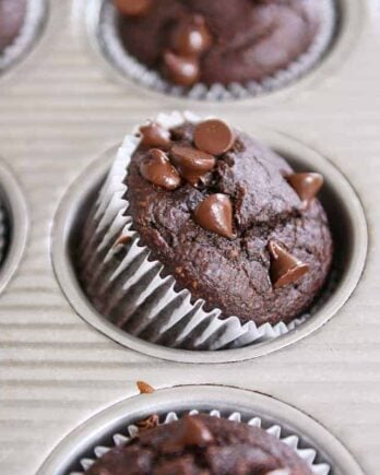 Double chocolate banana blender muffin propped on side in metal tin.