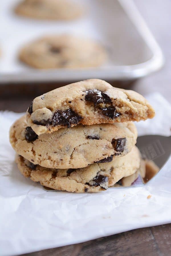 Chocolate chip cookies stacked on a metal spatula with the top cookie split in half.