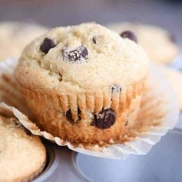 Easy one-bowl chocolate chip muffin unwrapped sitting on top of muffin tin.