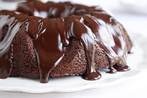 A chocolate bundt cake topped with chocolate ganache running down the sides of the cake.