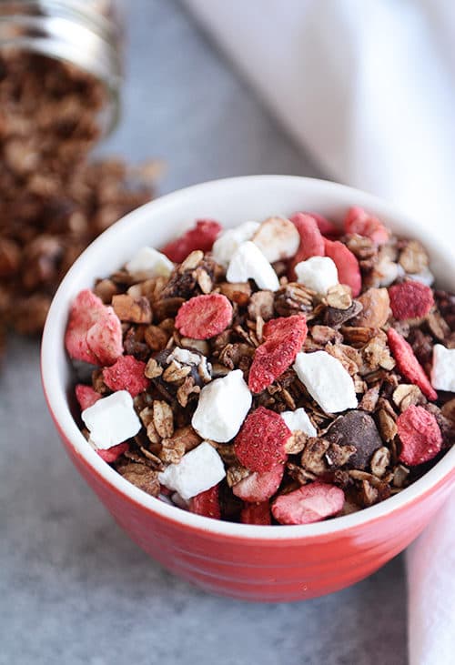 A bowl full of chocolate granola, freeze dried strawberries, and yogurt bites.