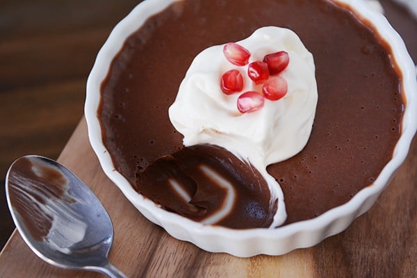 A top view of a ramekin with cooked chocolate cream with a bite taken out.