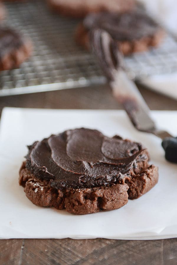A chocolate sugar cookie with a thick layer of chocolate frosting on top.