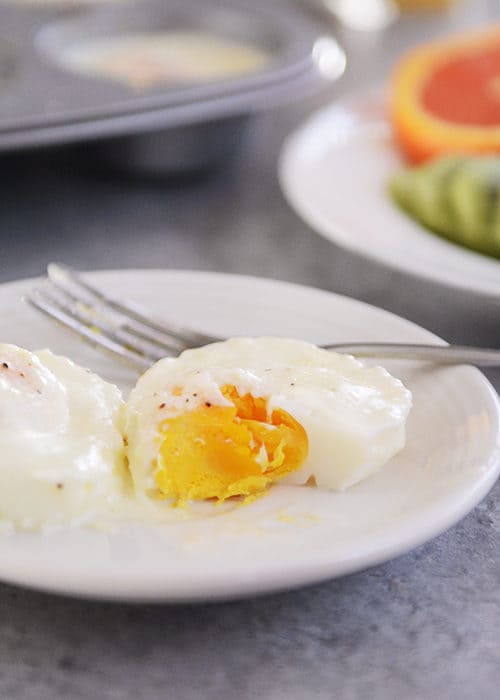 A white plate with a cooked egg with a bite taken out.