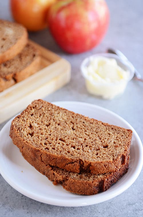 Two thick slices of applesauce quick bread stacked on each other on a white plate.