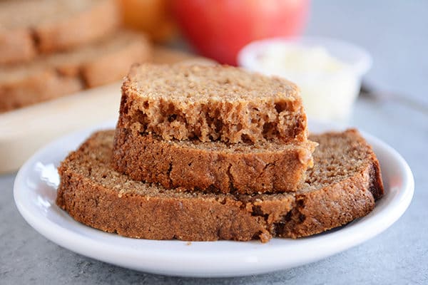 Thick slices of cinnamon applesauce quick bread stacked on a white plate.