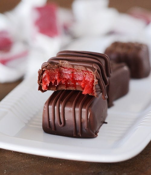 A chocolate dipped cinnamon caramel with a bite taken out on top of another dipped caramel.