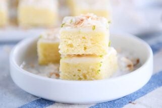 Toasted coconut lime bars stacked on white circle plate.