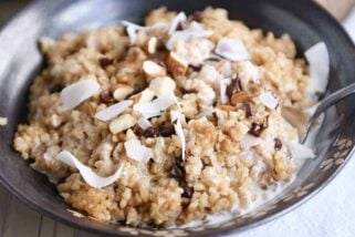 Coconut milk steel cut oats in brown bowl with chocolate chips, almonds and coconut.