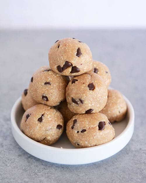A stack of chocolate chip cookie dough bites on a small white plate.