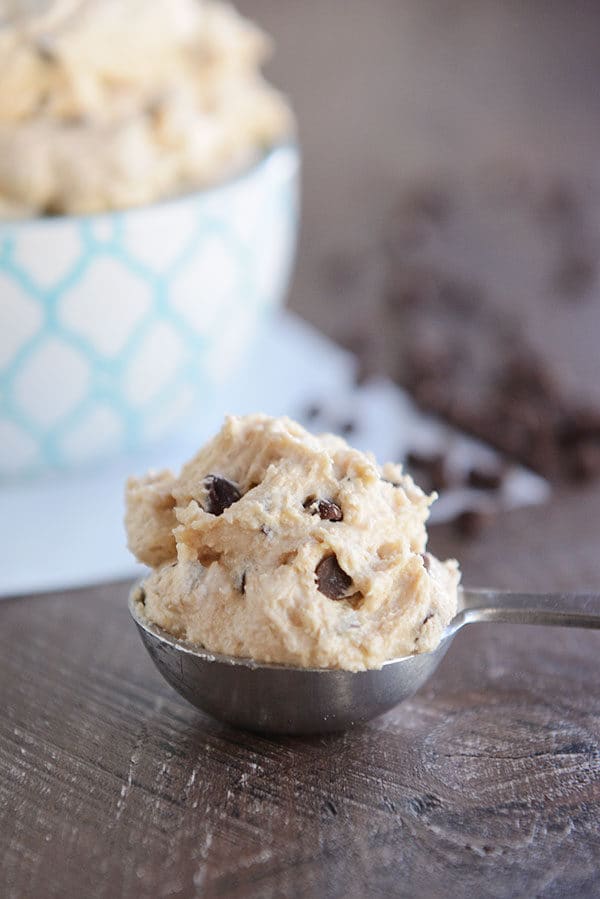 A measuring spoon full of a heaping scoop of cookie dough frosting.