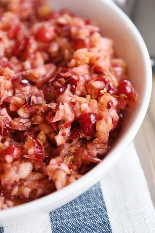 Close up view of fresh cranberry apple relish in white bowl.