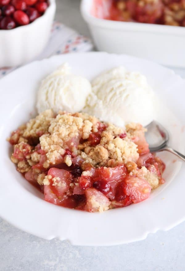 Close up view of bowl of cranberry pear crumble with vanilla ice cream.