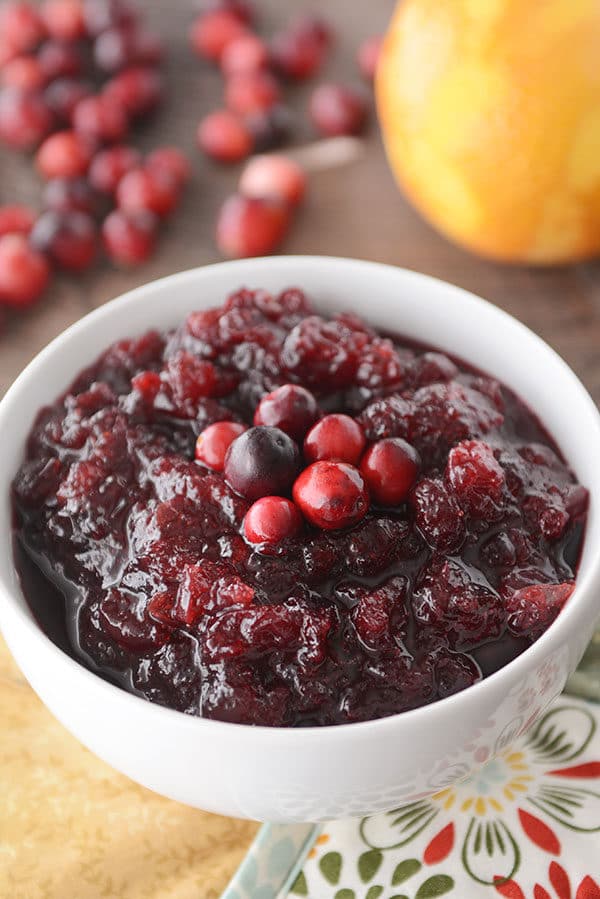 A white bowl of fresh cranberry sauce topped with a few fresh berries.