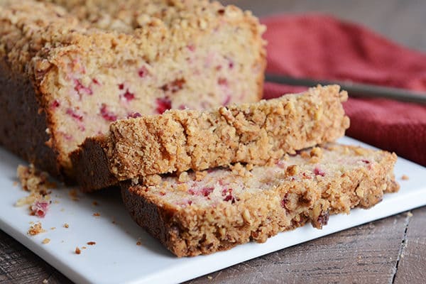Streusel-topped cranberry quick bread with two slices cut off on a white plate. 