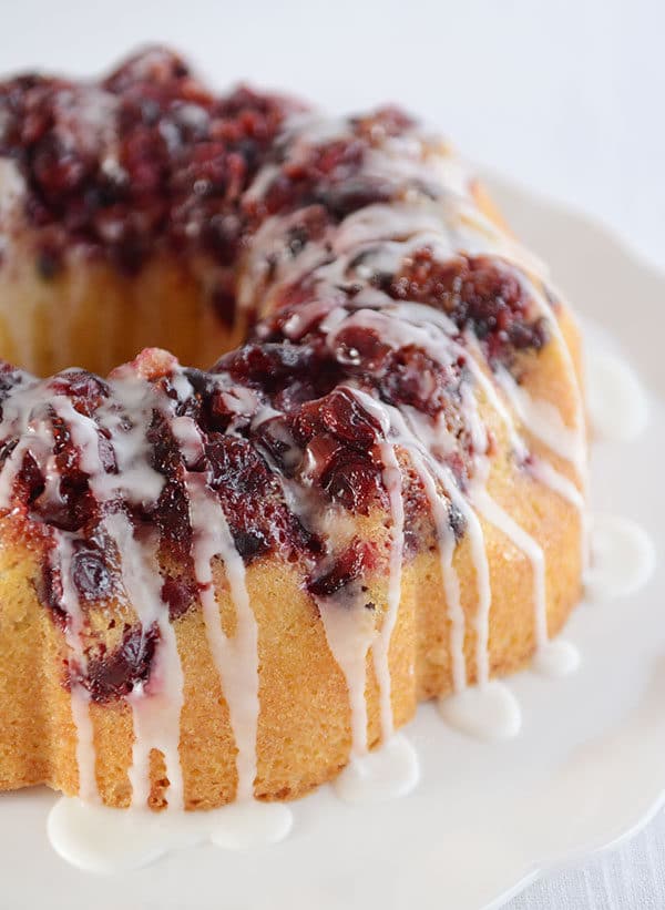 A glazed cranberry topped lemon bundt cake on a white platter.