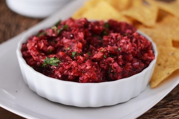 A white platter with a ramekin of cranberry salsa and tortilla chips. 