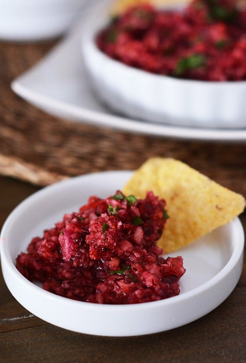 A scoop of cranberry salsa on top of a tortilla chip. 