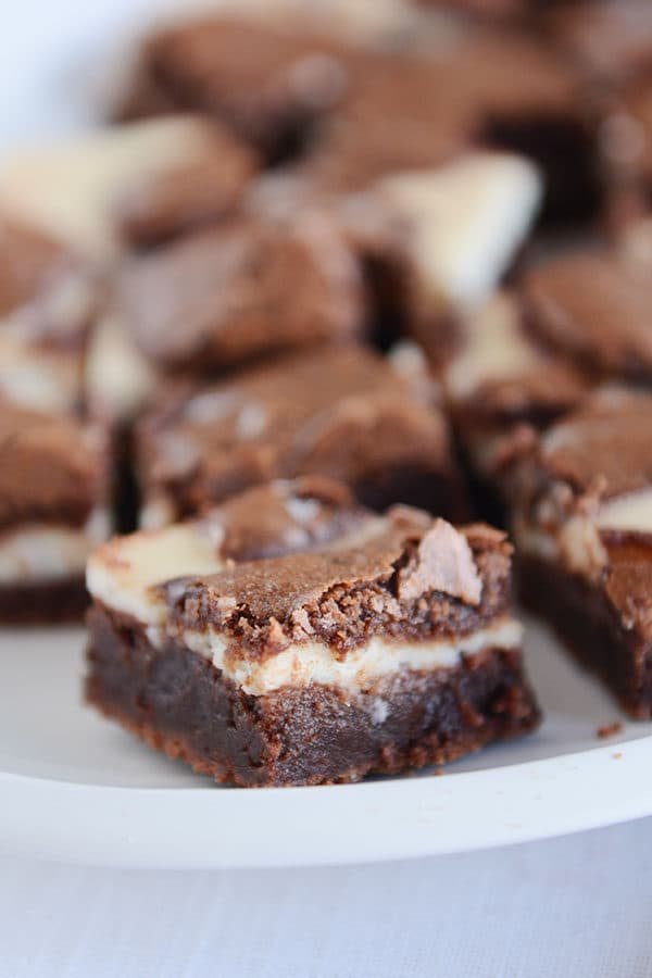 A white plate of layered cream cheese and chocolate brownies.