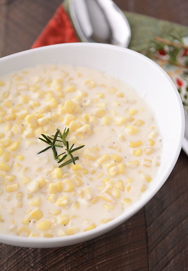 A large oval white bowl full of parmesan cream corn.