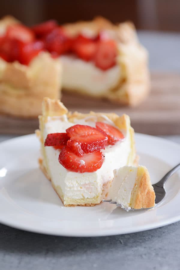A slice of strawberry cream puff cake with a bite taken out.