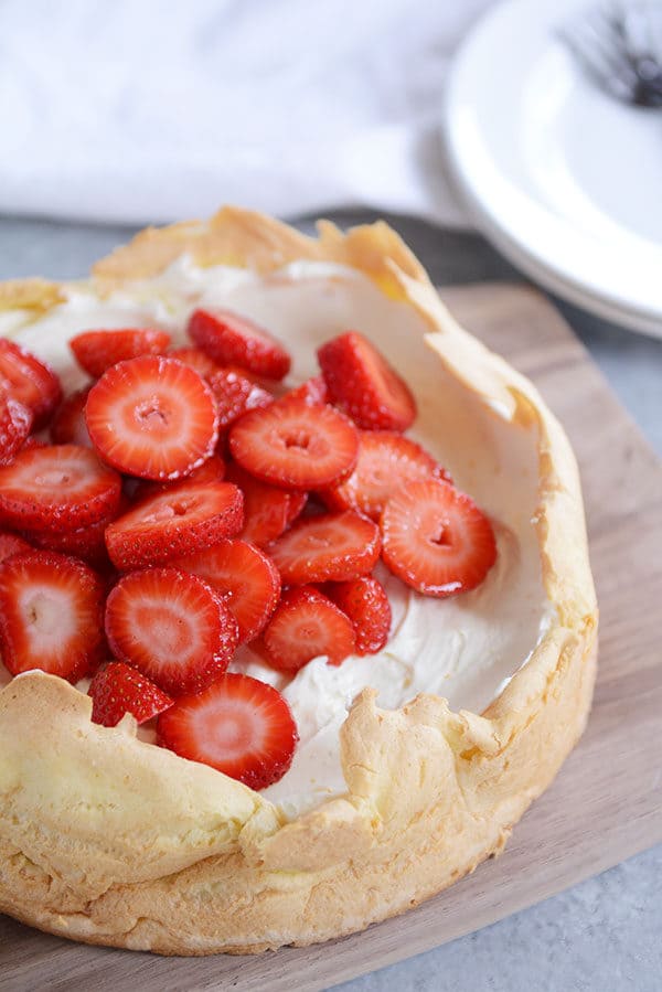 A cream puff cake topped with sliced strawberries.