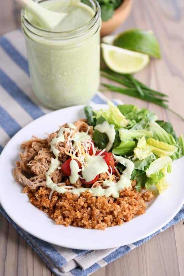 Plate of quinoa and pork with cilantro lime dressing drizzled over the top.