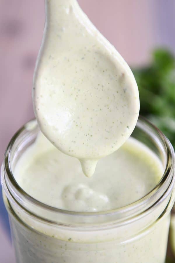 Jar of cilantro lime dressing with spoon.