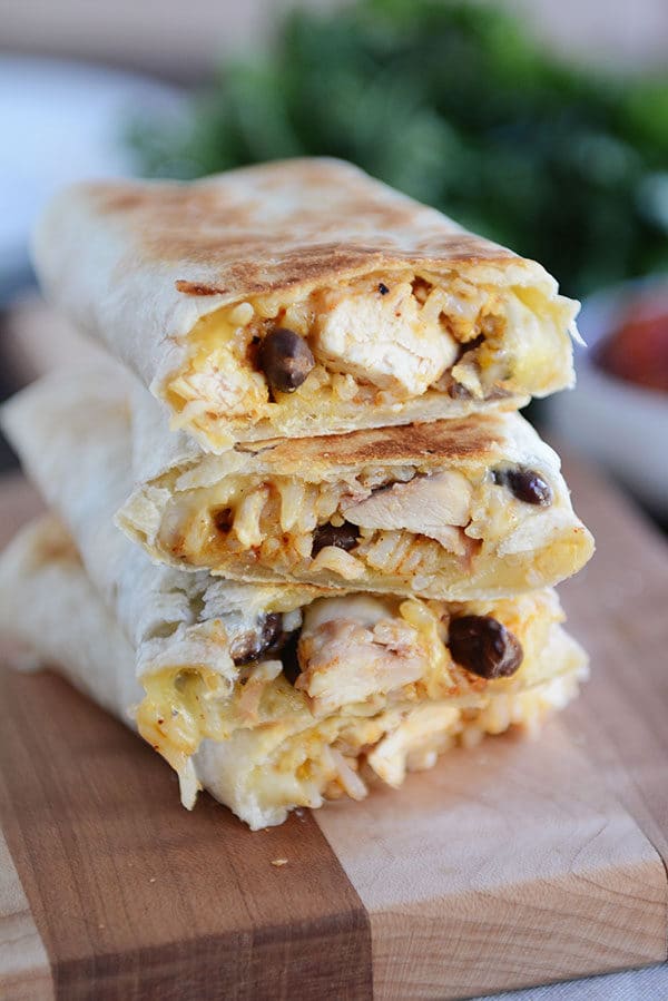 Four southwest chicken wraps stacked on top of each other on top of a cutting board. 