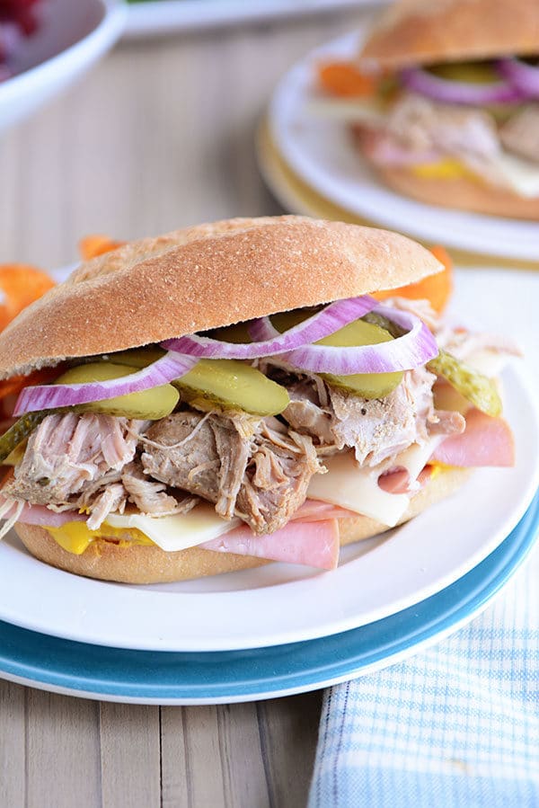 A large Cuban sandwich on a hoagie bun on a white plate. 