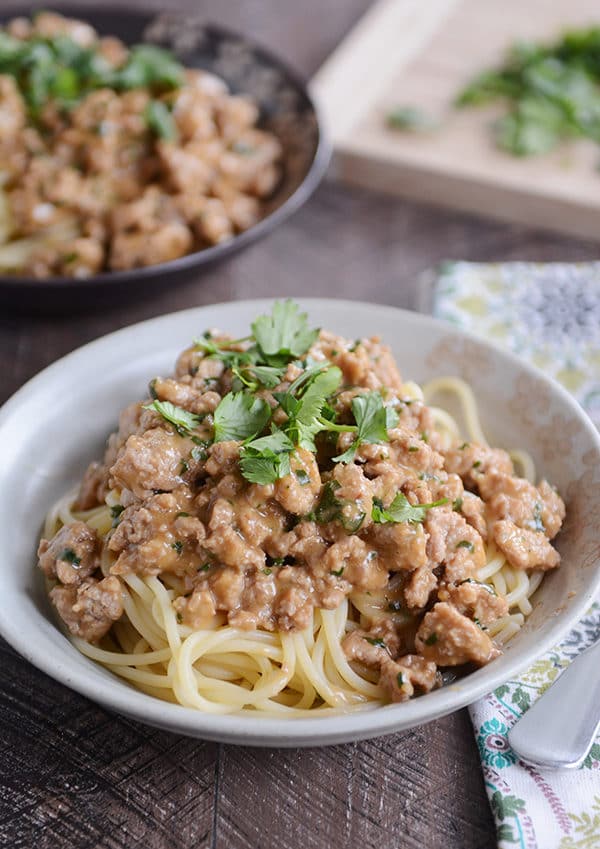 A white bowl full of pasta topped with a saucy ground beef mixture and cilantro.