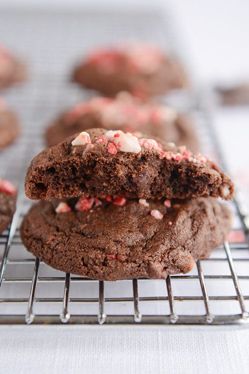A chocolate cookie split in half on top of another cookie with crushed peppermint on top. 