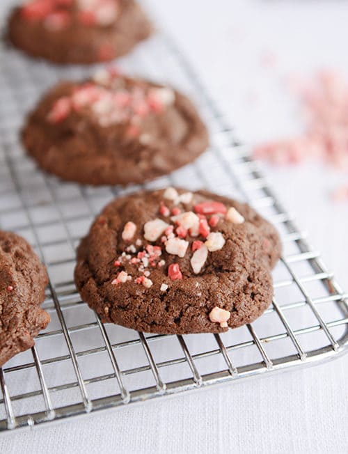 Chocolate cookies on a cooling rack with crushed peppermints on top.