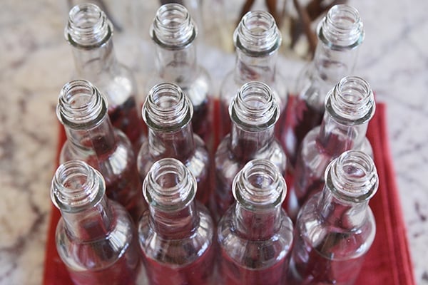 Top view of twelve glass bottles with vanilla beans inside.