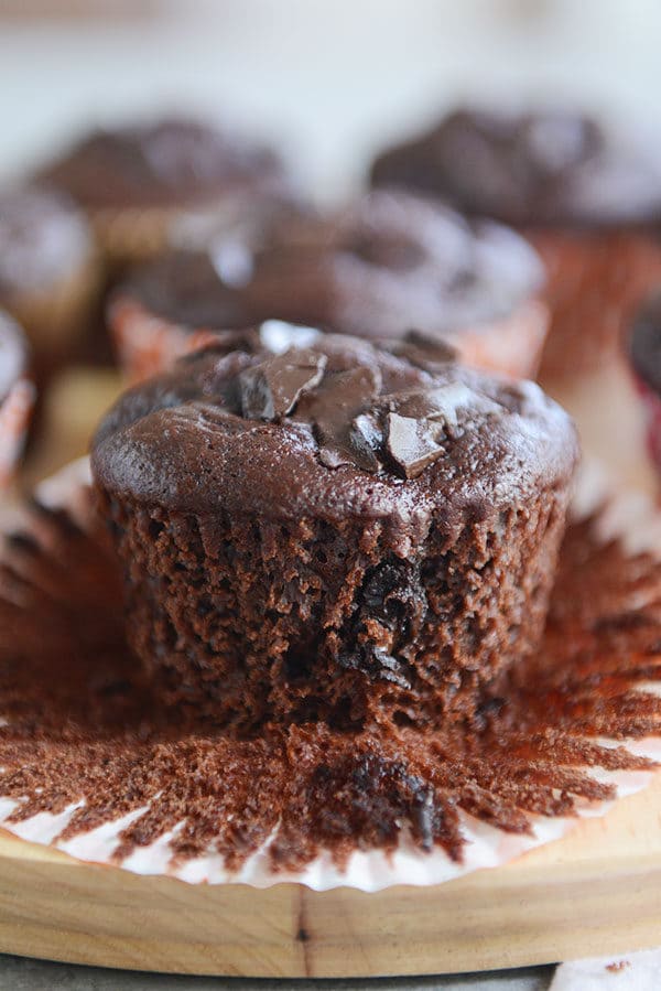 A chocolate chunk muffin sitting on top of a muffin liner.