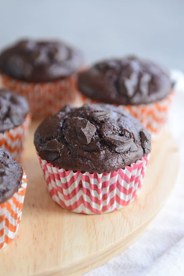 Chocolate chunk muffins in striped red and orange muffin liners.
