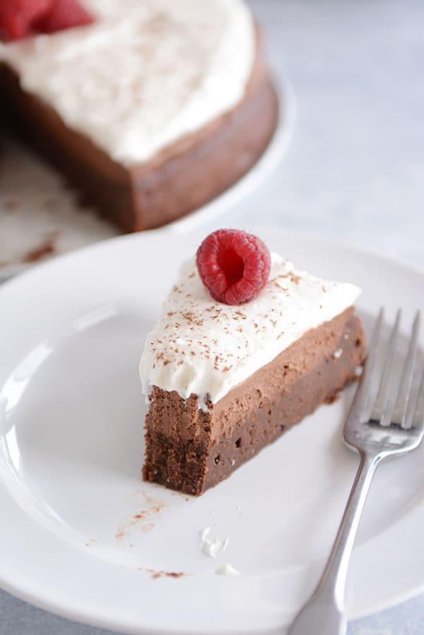 A slice of chocolate mousse torte with a bite taken out on a white plate.