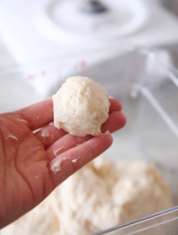 Rolling small ball of cinnamon roll dough in hands.