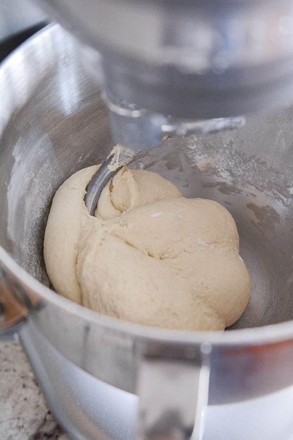 Bread dough mixing inside the bowl of a KitchenAid mixer.
