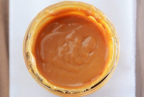 Top down view of a mason jar full of golden brown dulce de leche.