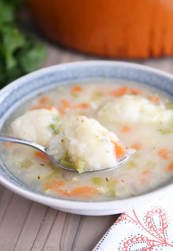 Blue bowl with spoonful of chicken dumpling soup.