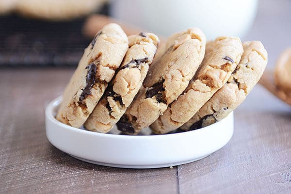Five peanut butter chocolate chip cookies stacked side-by-side in a white ramekin.
