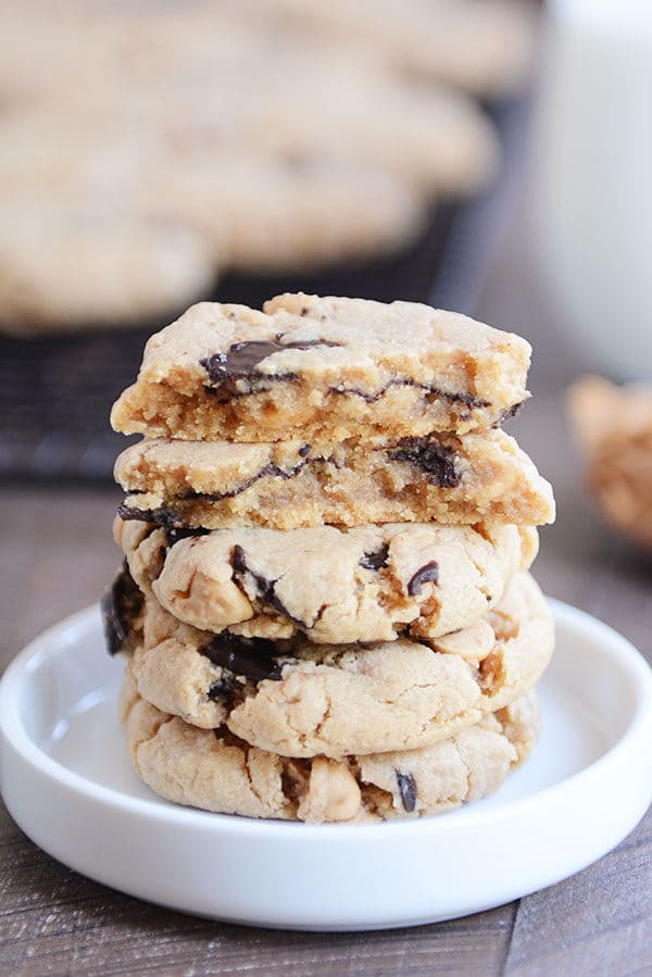 A stack of chocolate chip peanut butter cookies with the top cookie split in half in a white ramekin.