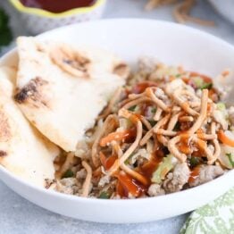 Ground turkey, cabbage, naan in white bowl drizzled with sweet and sour sauce.