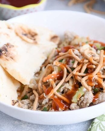 Ground turkey, cabbage, naan in white bowl drizzled with sweet and sour sauce.