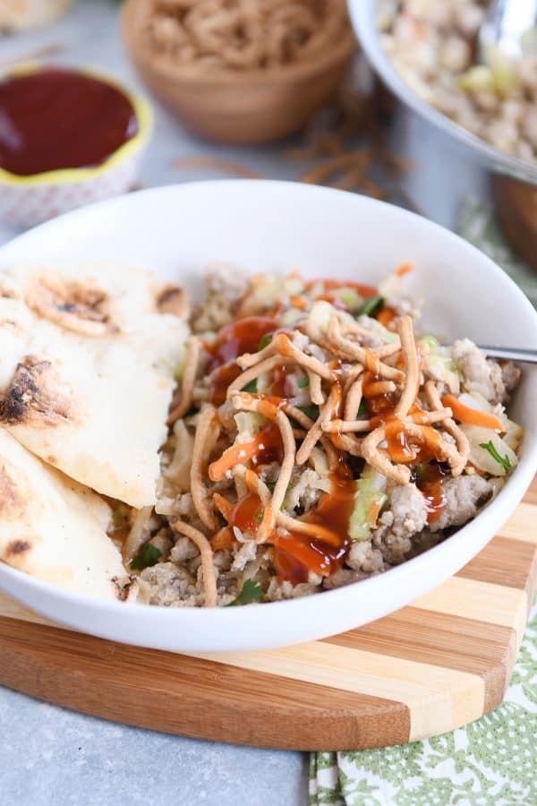 Ground turkey, cabbage, naan in white bowl drizzled with sweet and sour sauce.